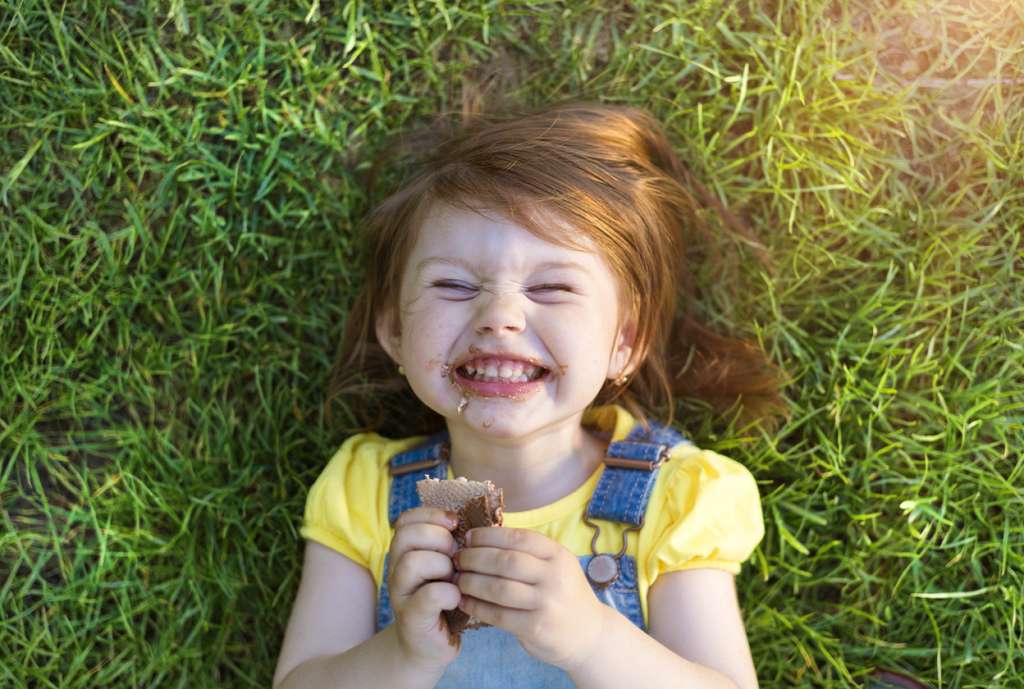 Young girl with chocolate face lying on a grass
