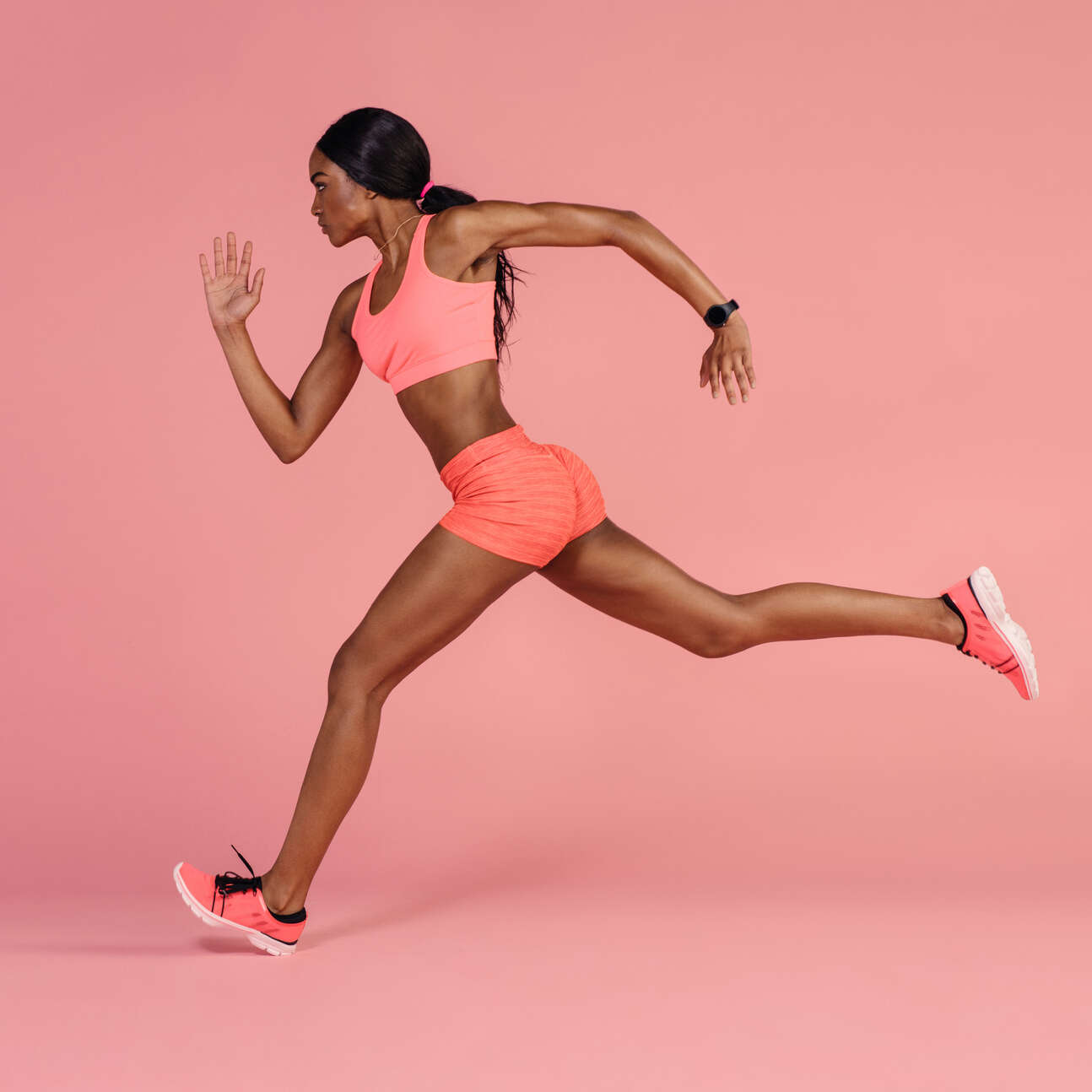 African female runner sprinting Fit and healthy woman running. African female runner sprinting on pink background.